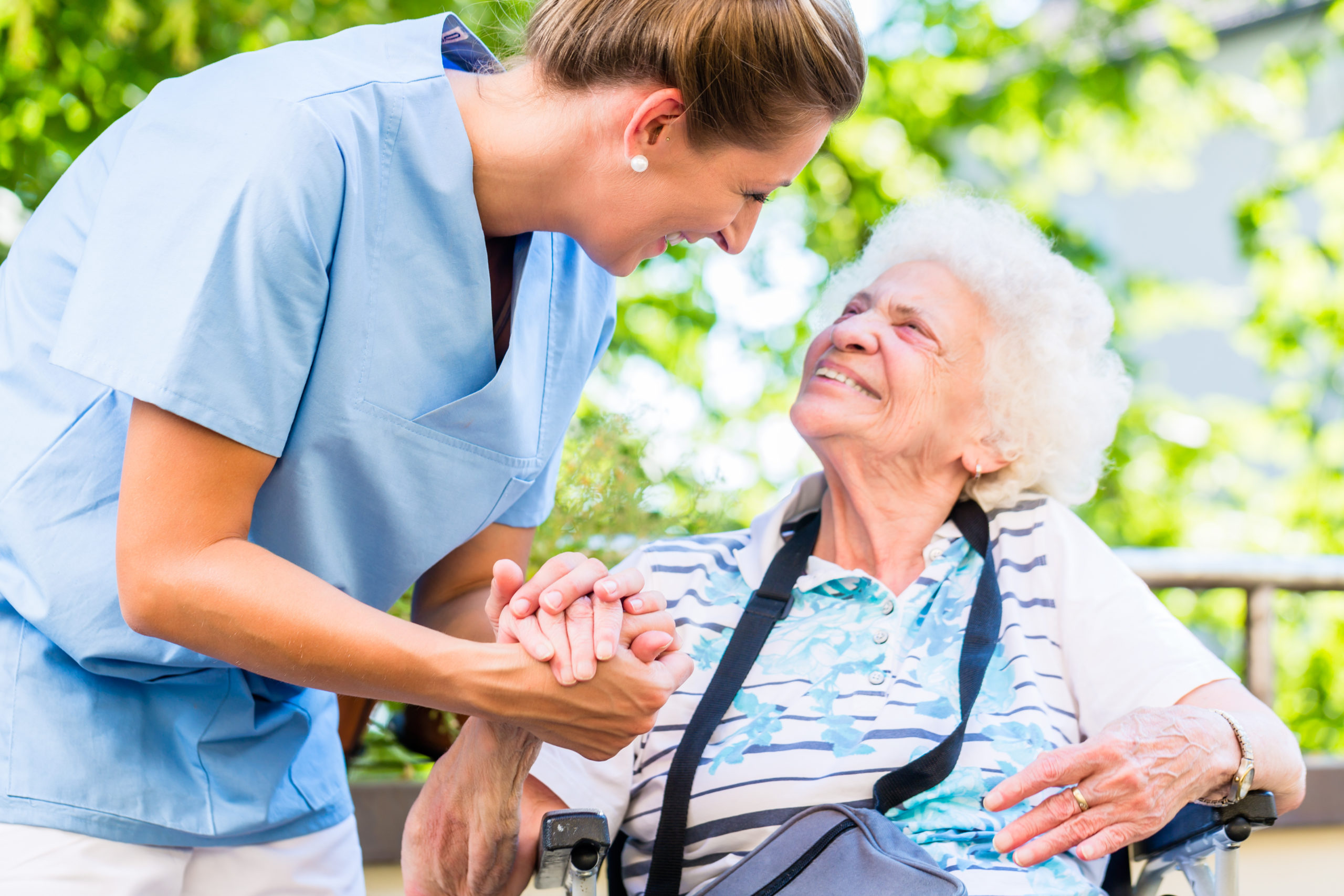 Pflegerin hält liebevoll die Hand einer Seniorin